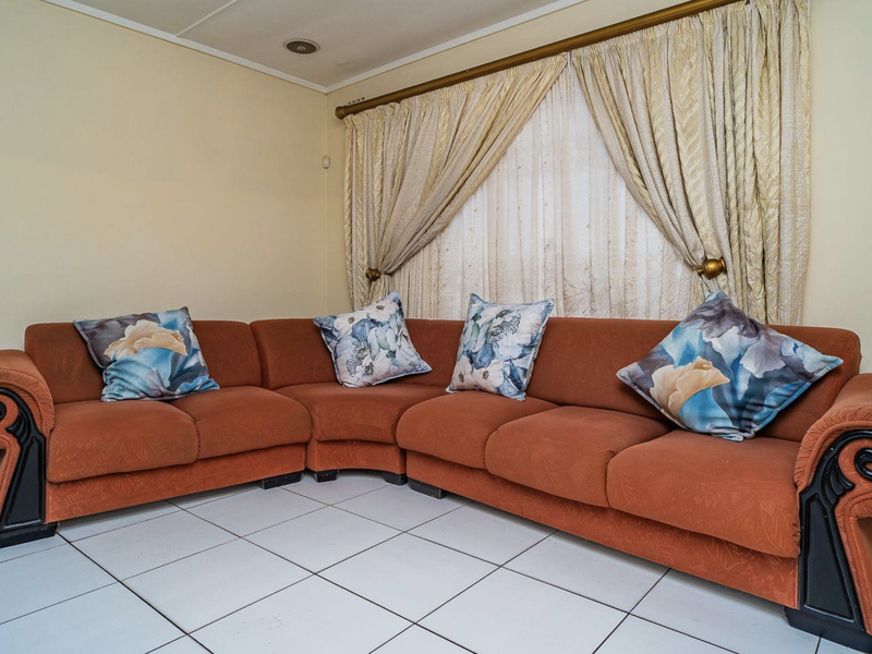 A living room area featuring white tiled flooring and recessed ceiling lighting, providing a functional space for relaxation.