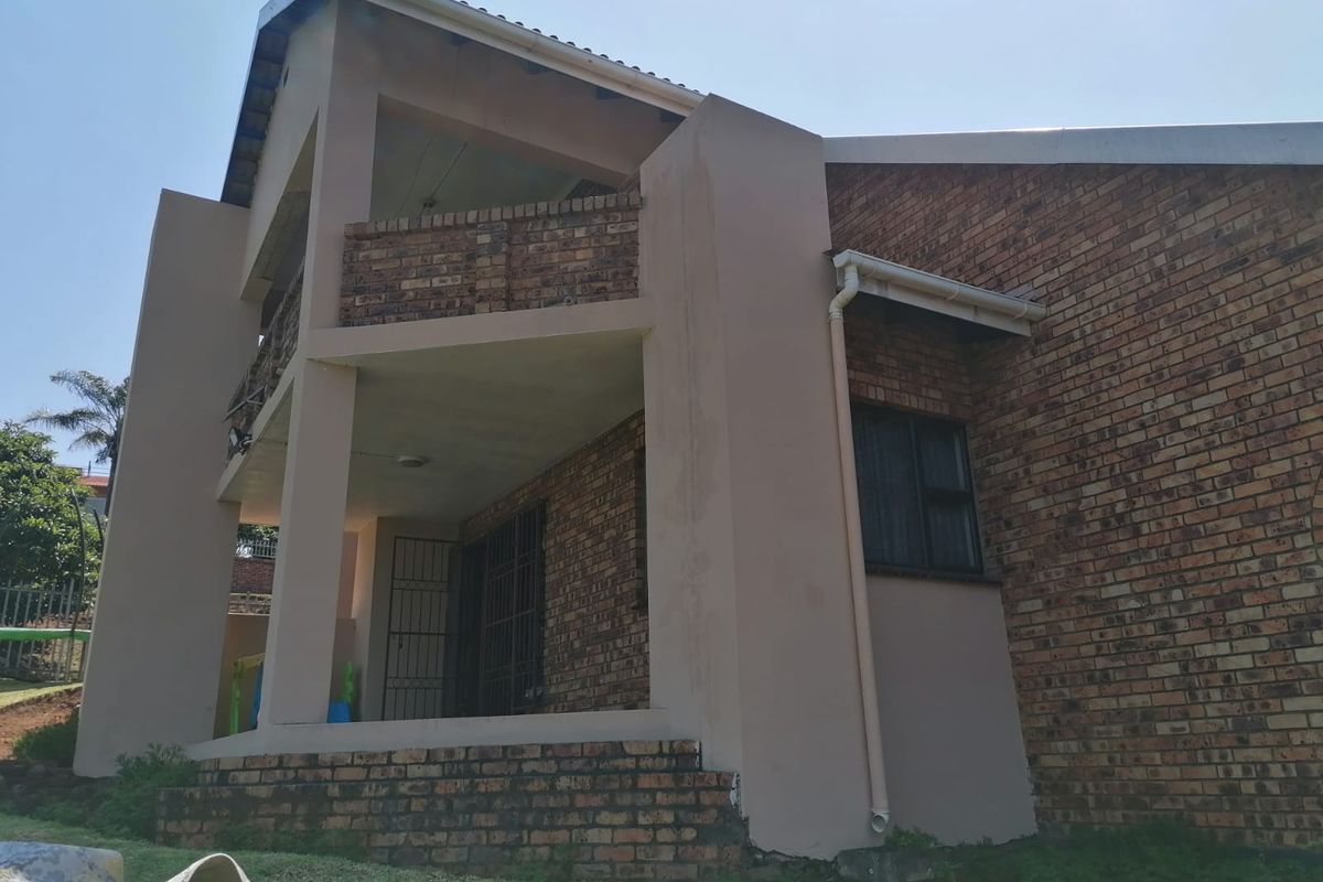 Rear elevation of a double-story face brick house featuring a covered ground floor patio and an upper-level balcony.