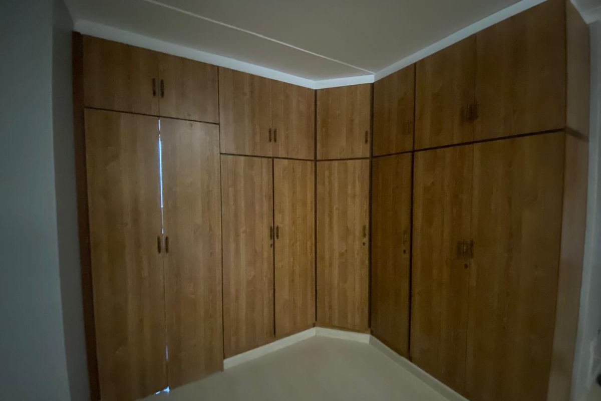 A bedroom featuring extensive floor-to-ceiling built-in wooden cupboards providing ample storage space.