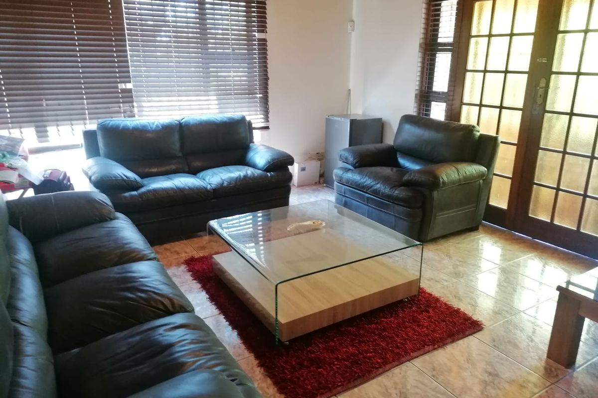 A living room featuring tiled flooring, wooden venetian blinds, and access to the outdoors via glass-paned french doors.