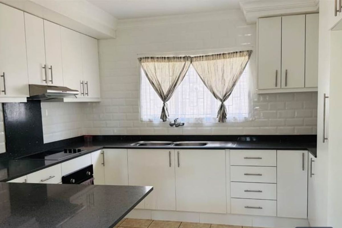 A functional kitchen featuring white cabinetry, contrasting black granite countertops, a subway tile backsplash, and integrated stainless steel appliances.