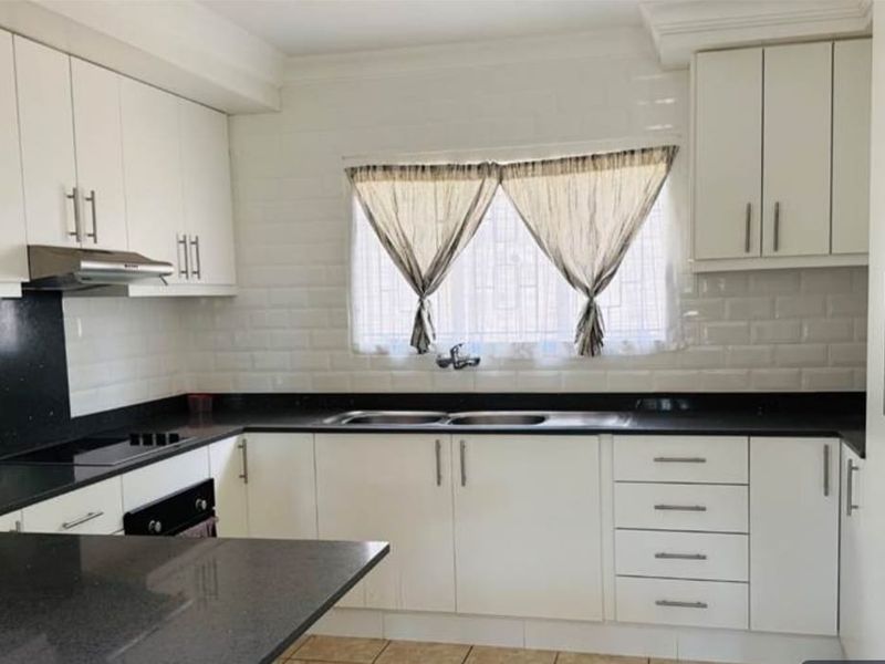 A functional kitchen featuring white cabinetry, contrasting black granite countertops, a subway tile backsplash, and integrated stainless steel appliances.
