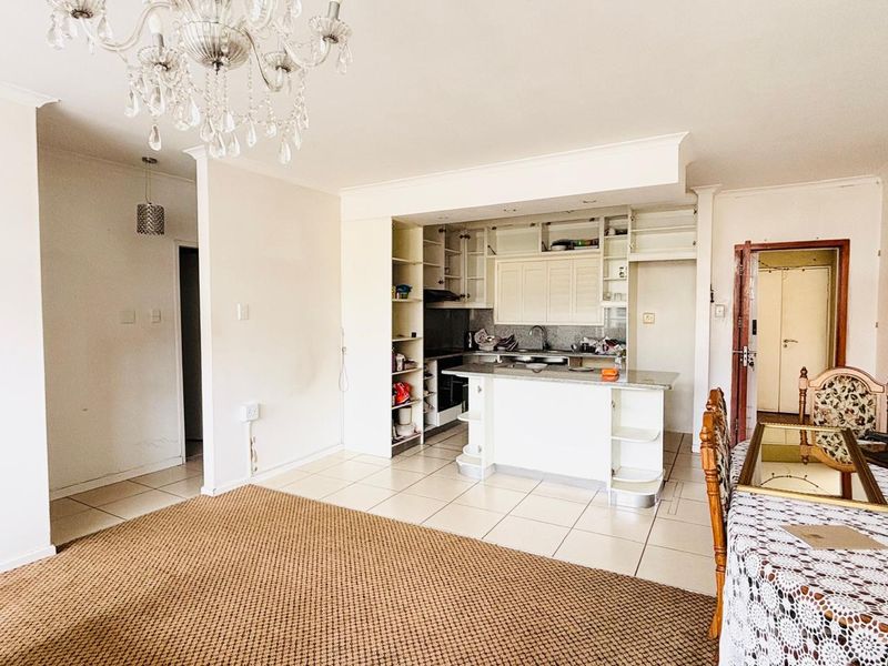 Open plan living and kitchen area featuring tiled floors, built-in cabinetry with granite countertops, and a central breakfast bar.