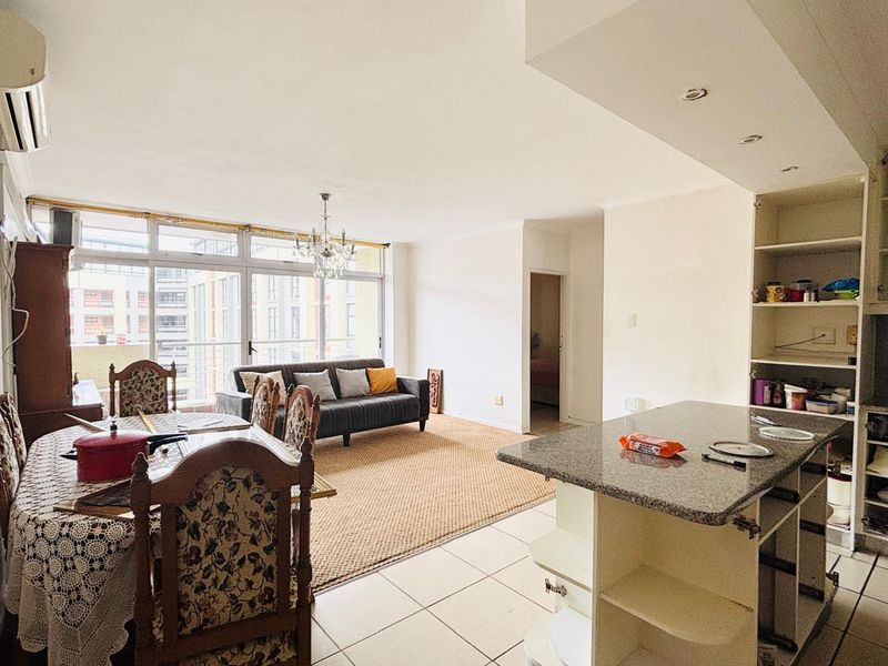 Open-plan living and dining area featuring a granite kitchen island, tiled flooring, and large sliding doors leading to a balcony.