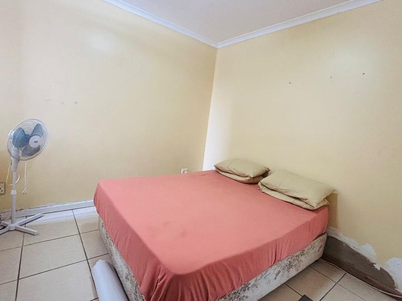 A bedroom featuring tiled flooring and plain walls, currently requiring cosmetic repairs to the wall plaster and skirting boards.
