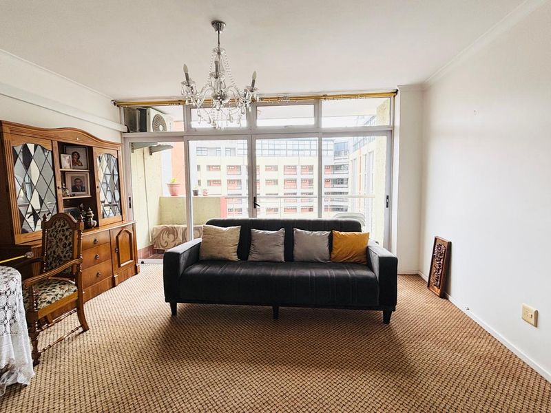 A living room featuring large glass sliding doors leading to a balcony, providing natural light and an urban view.