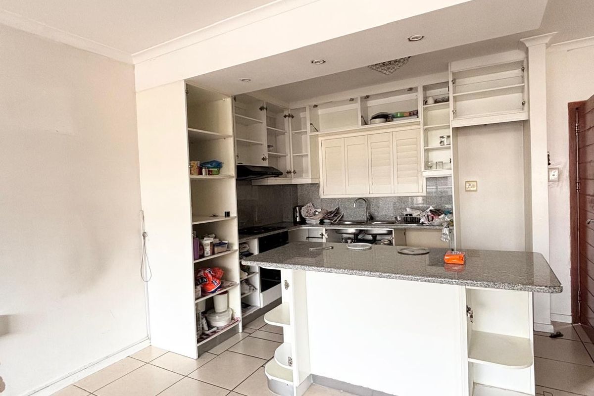 A functional kitchen featuring granite countertops, a breakfast bar, and ample built-in cabinetry, currently requiring some cosmetic updates to cabinet doors and finishes.