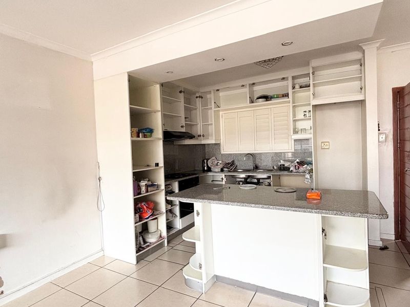A functional kitchen featuring granite countertops, a breakfast bar, and ample built-in cabinetry, currently requiring some cosmetic updates to cabinet doors and finishes.