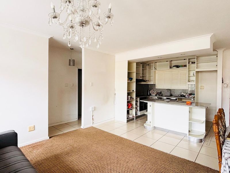 Open-plan living area featuring a kitchen with built-in cabinetry, granite countertops, and tiled flooring, seamlessly connected to the main living space.