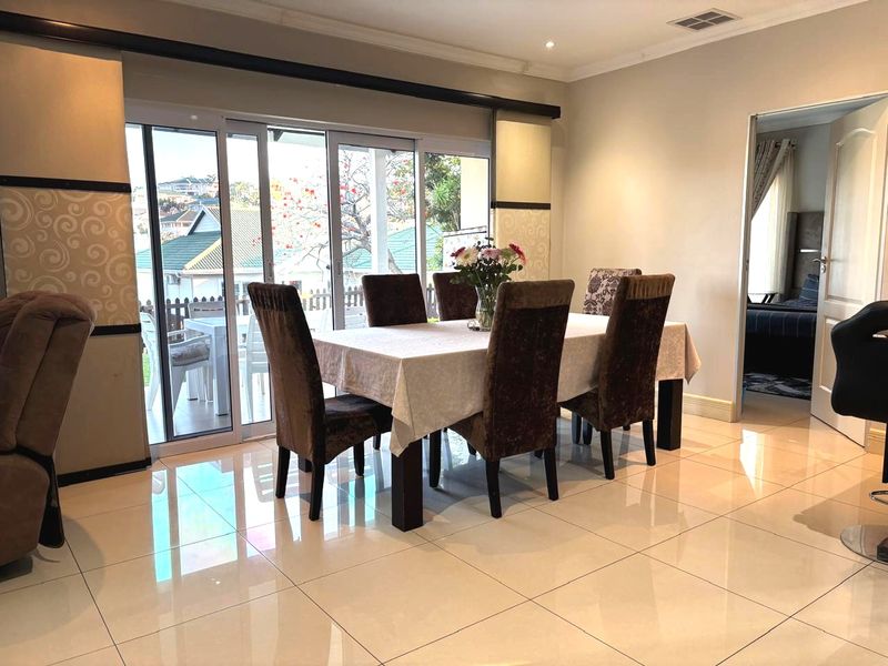 Bright dining area featuring polished porcelain floor tiles, recessed lighting, and large sliding glass doors providing access to the outdoor patio.