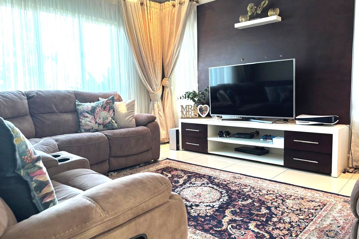 A comfortable living room featuring tiled flooring, a dark accent wall with a floating shelf, and large windows with floor-to-ceiling curtains.