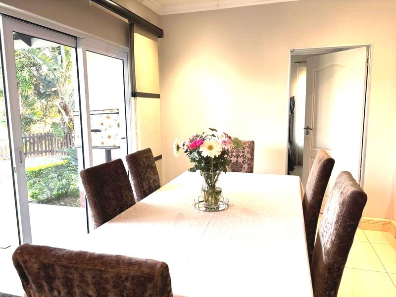 A bright dining room featuring tiled flooring and a large sliding glass door providing access to the outdoor area.