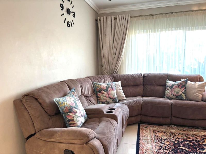 A comfortable living room featuring tiled flooring, coved ceilings, and large windows with installed curtain tracks, providing a bright and inviting atmosphere.