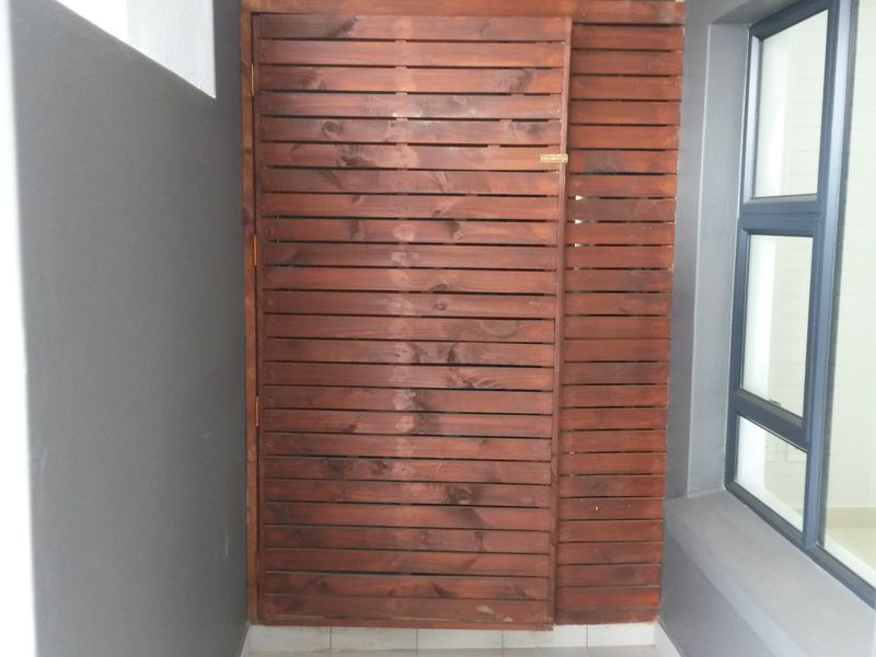 A functional utility area featuring a timber slat screen enclosure and modern aluminium window frames, providing a clean and organized space.