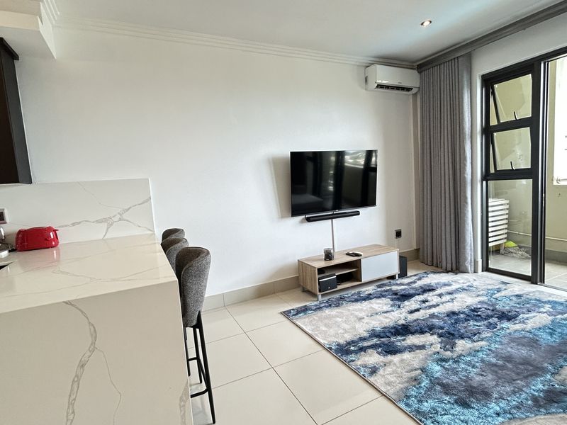 Modern open-plan living area featuring a stone-topped kitchen island, tiled floors, split-system air conditioning, and direct access to a private balcony.