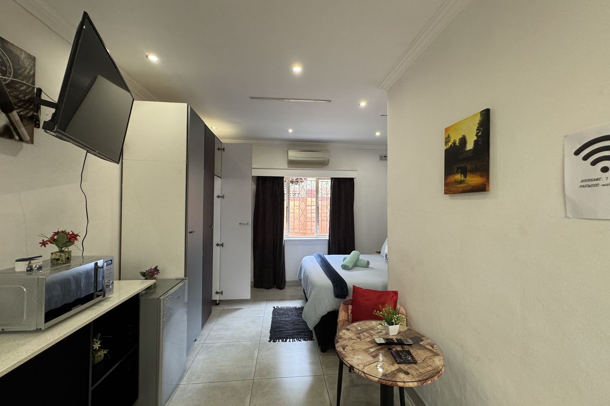 A compact bedroom featuring built-in cabinetry, tiled flooring, recessed ceiling lighting, and a wall-mounted air conditioning unit.