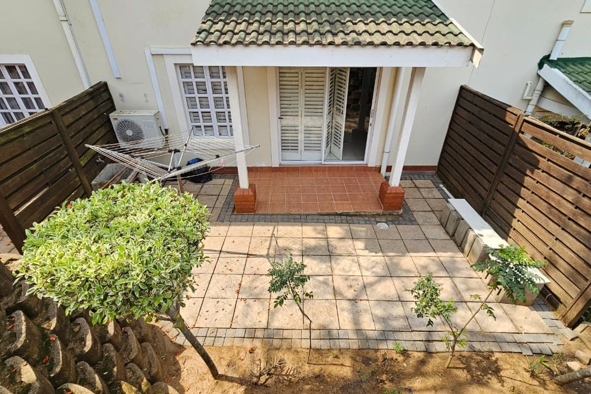 A private rear patio area featuring tiled flooring, a covered entrance, and timber privacy fencing, providing a functional outdoor space for the townhouse.