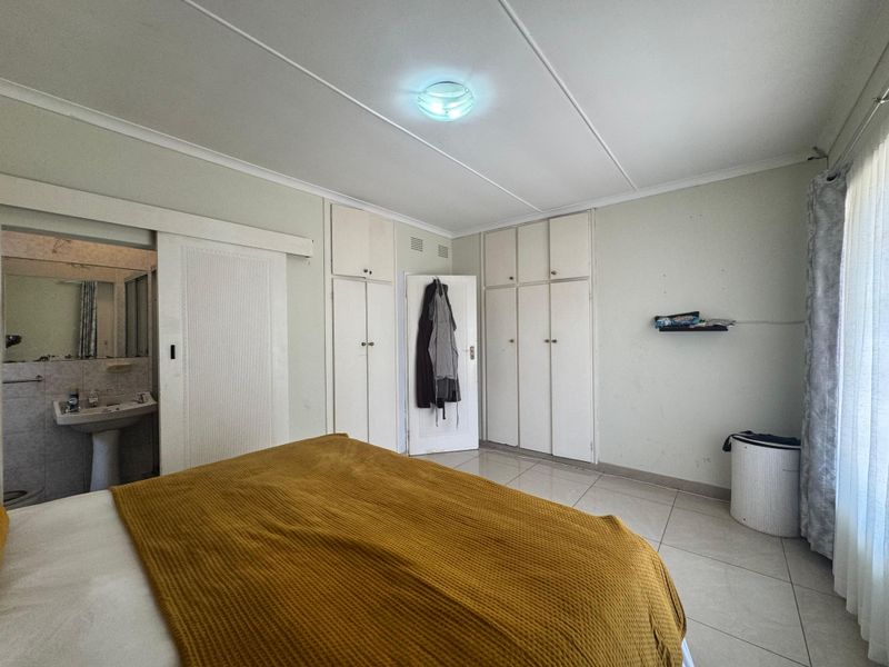 Bedroom featuring tiled flooring, built-in cupboards, and direct access to an en-suite bathroom.