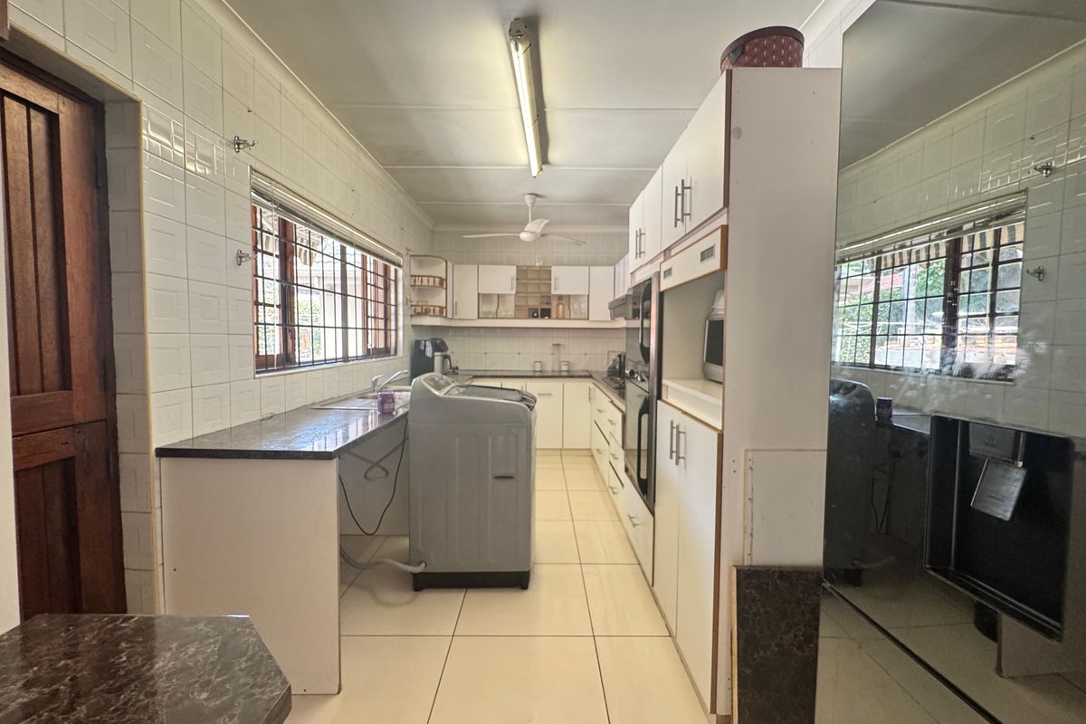A functional kitchen featuring tiled walls and floors, built-in cabinetry, and an integrated oven, offering a practical layout with potential for modern updates.