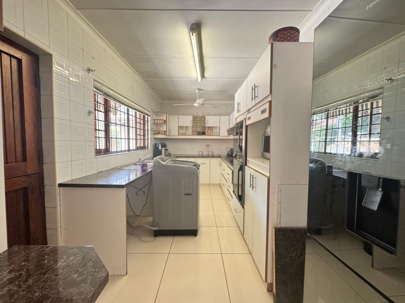 A functional kitchen featuring tiled walls and floors, built-in cabinetry, and an integrated oven, offering a practical layout with potential for modern updates.