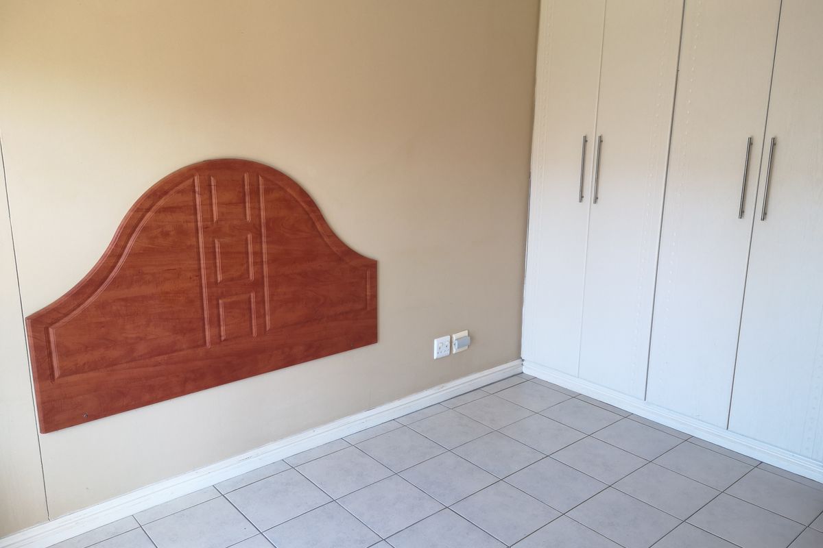 A bedroom featuring tiled flooring, a built-in wardrobe, and a wall-mounted headboard.