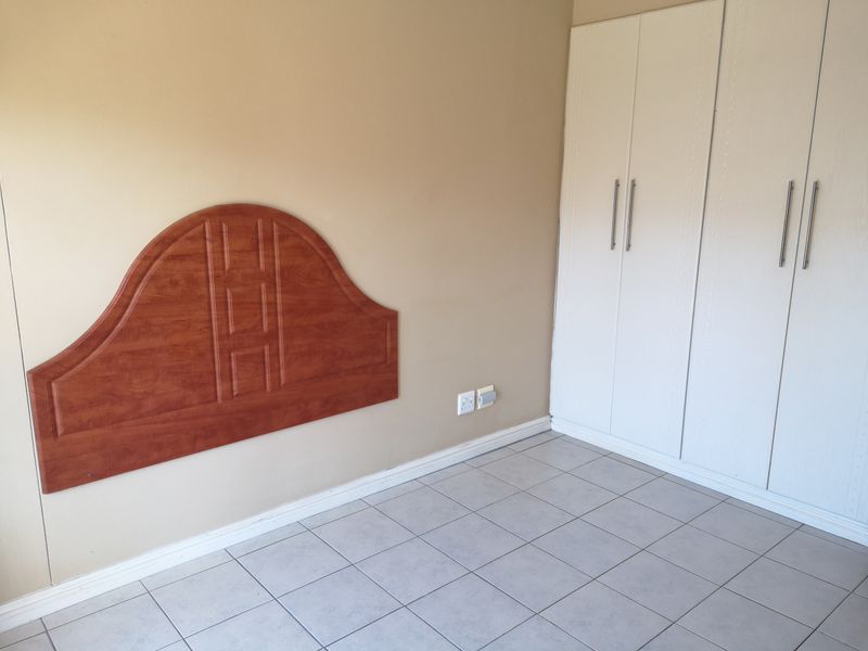 A bedroom featuring tiled flooring, a built-in wardrobe, and a wall-mounted headboard.