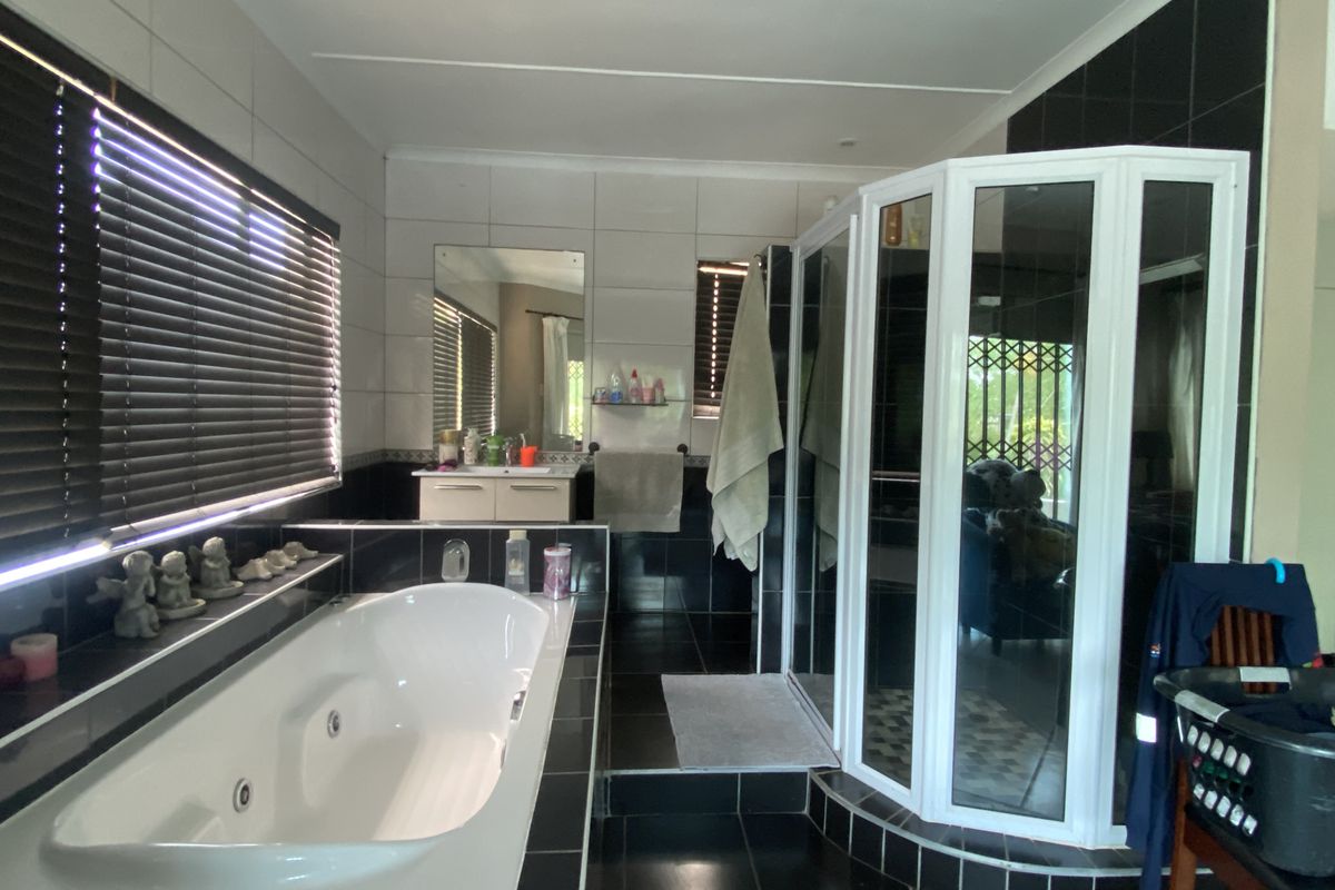 A spacious bathroom featuring a built-in corner spa bath, a separate glass-enclosed shower, and tiled wall and floor finishes.