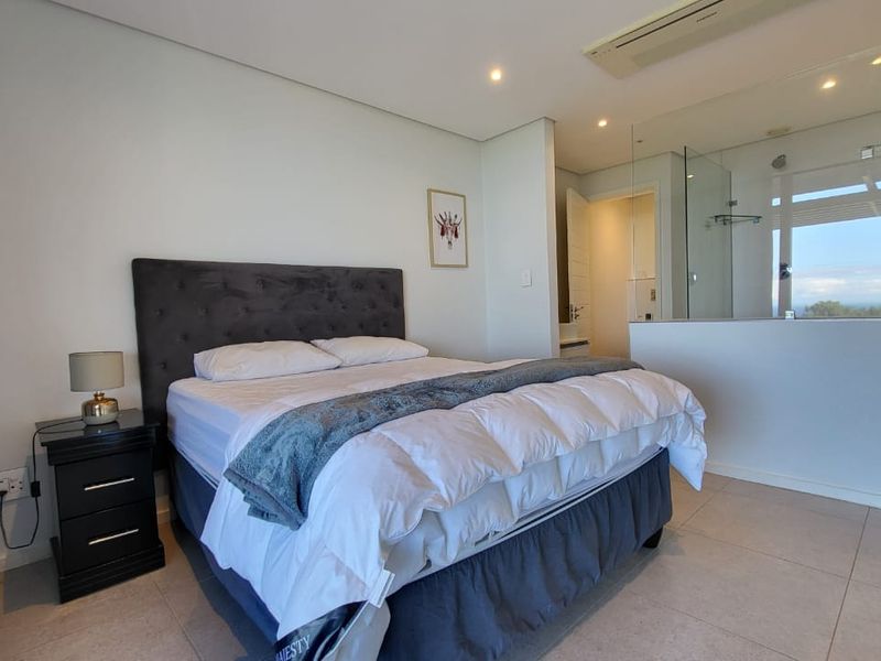 Modern bedroom featuring tiled flooring, recessed lighting, ducted air conditioning, and an integrated glass-partitioned en-suite bathroom.