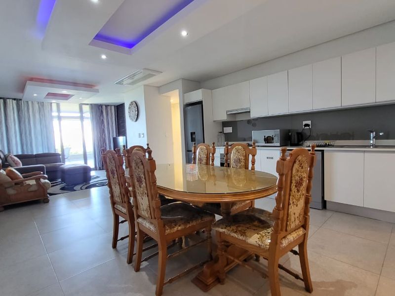 Spacious open-plan living and dining area featuring modern kitchen cabinetry, recessed ceiling lighting, and large sliding doors leading to an outdoor space.