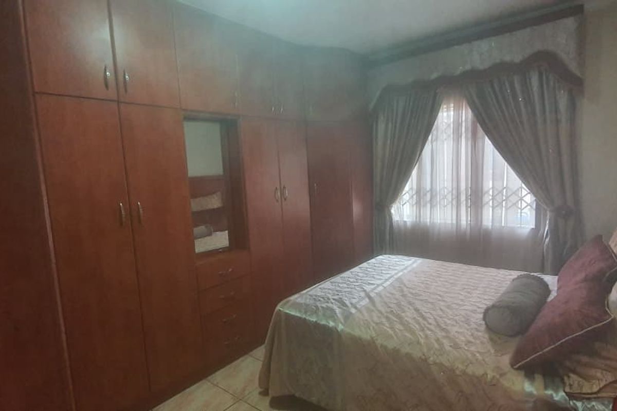 A bedroom featuring extensive built-in wooden cupboards, tiled flooring, and an integrated air conditioning unit, providing functional storage and climate control.
