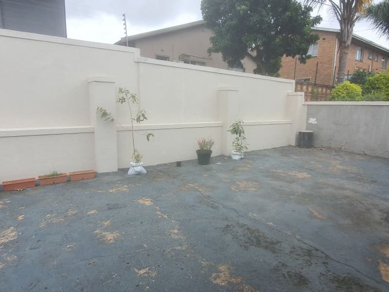A private rear courtyard area featuring a high boundary wall and worn concrete paving, offering potential for landscaping or outdoor living improvements.