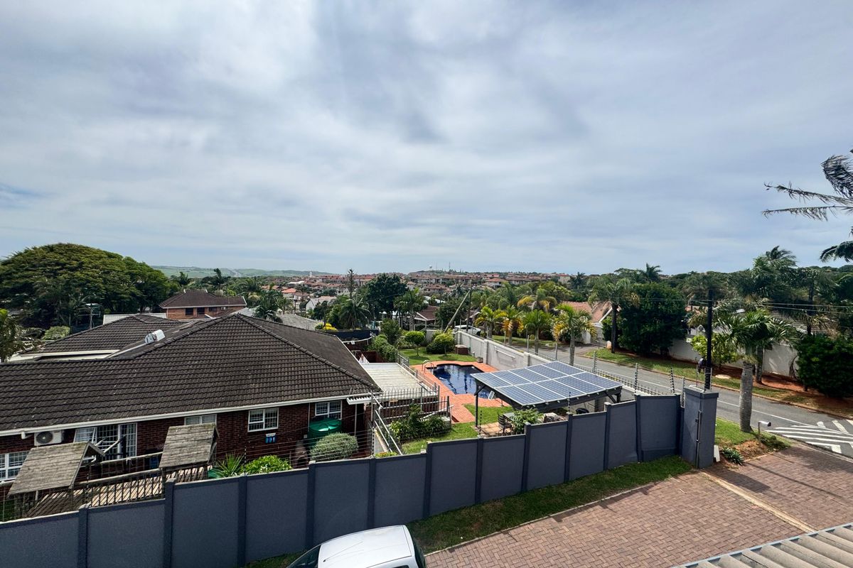 Elevated aerial view overlooking a residential neighborhood, featuring a private swimming pool, solar panel installation, and paved driveway area.