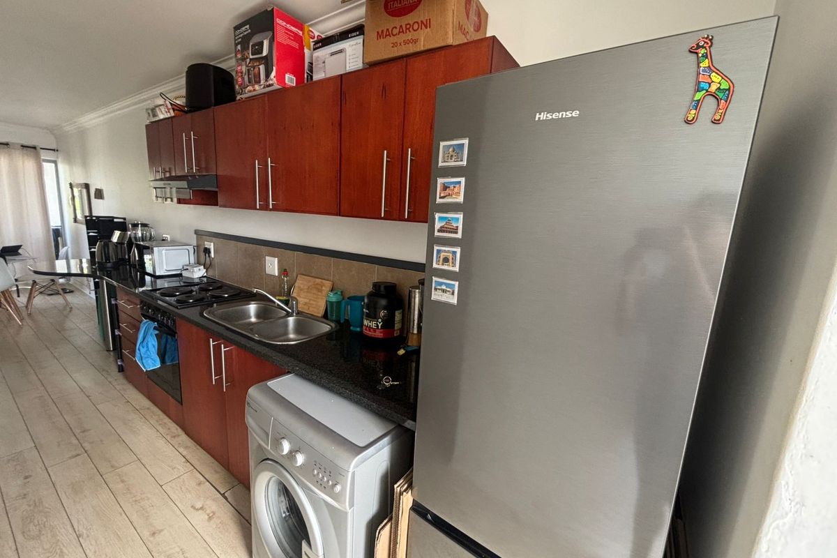 A functional kitchen featuring dark wood cabinetry, granite countertops, a double sink, and integrated appliances with tiled flooring and backsplash.