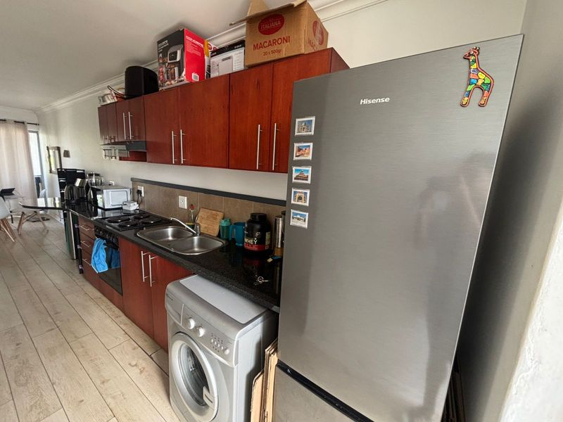 A functional kitchen featuring dark wood cabinetry, granite countertops, a double sink, and integrated appliances with tiled flooring and backsplash.