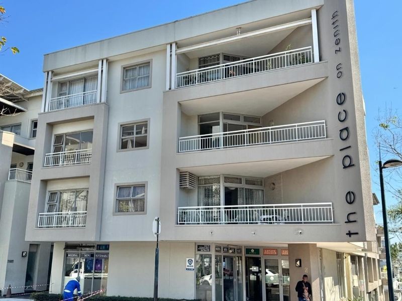 Front elevation of The Place on Zenith apartment building, featuring multi-level balconies with metal railings and ground-floor commercial retail spaces.