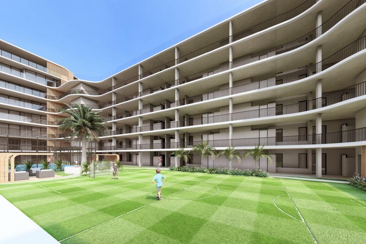 A modern apartment complex featuring a central courtyard with a landscaped lawn, recreational area, and multi-level balconies with sleek railings.