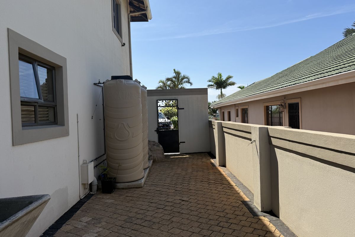 Side exterior walkway featuring paved flooring, a boundary wall, and installed water storage tanks.