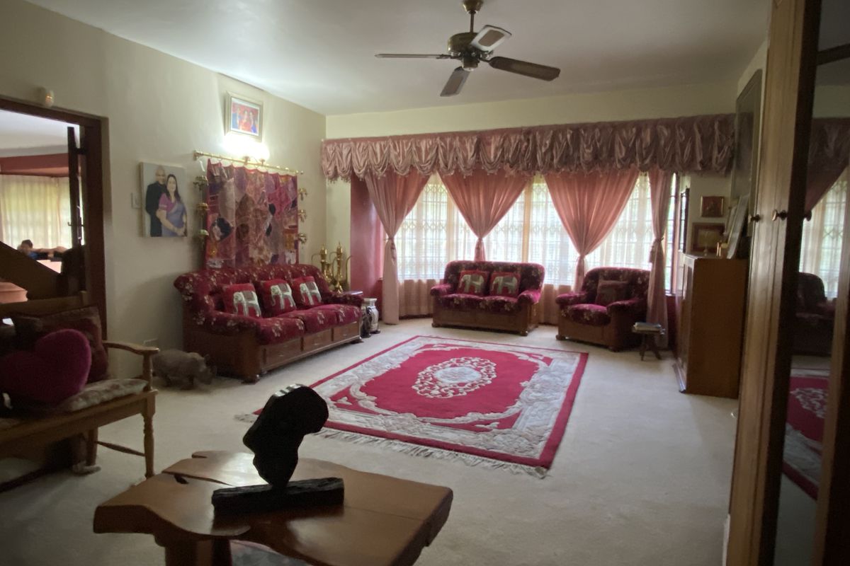 Spacious living room featuring a ceiling fan and large windows with traditional drapery, offering a comfortable and classic layout.