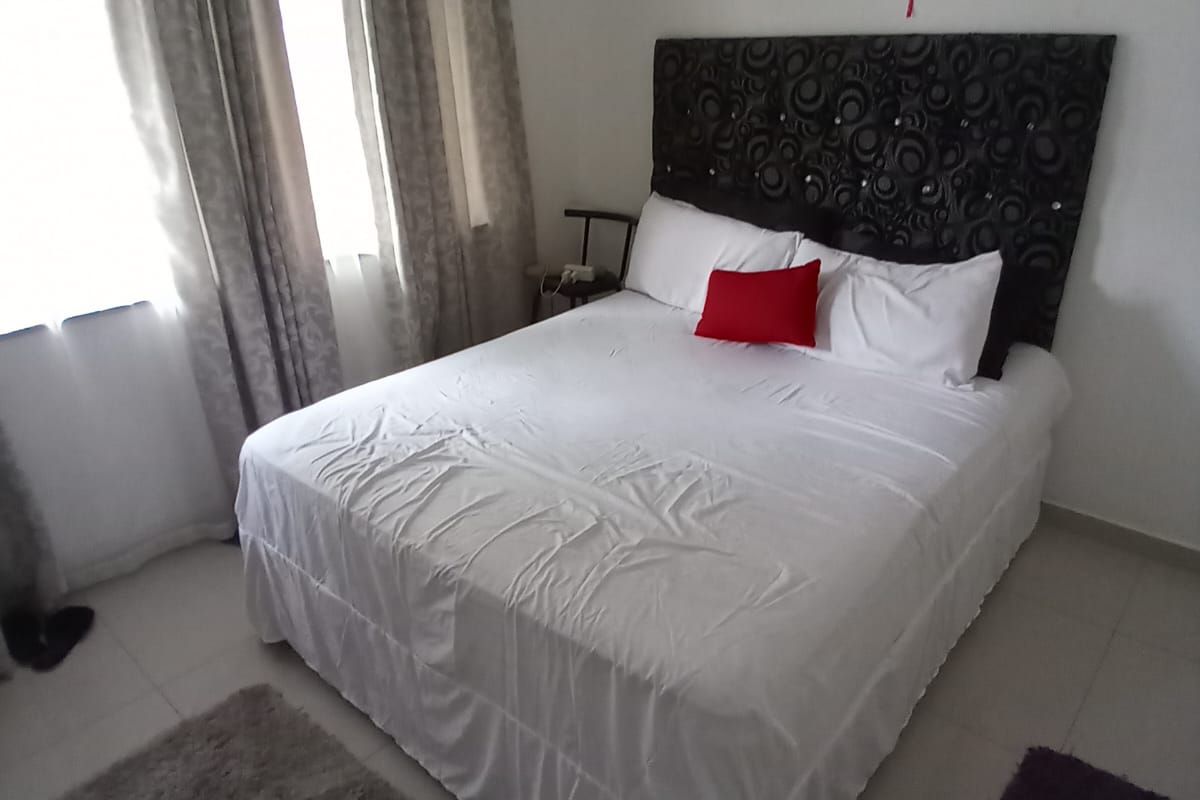 A bedroom featuring tiled flooring and a ceiling fan, providing a functional and neutral space.