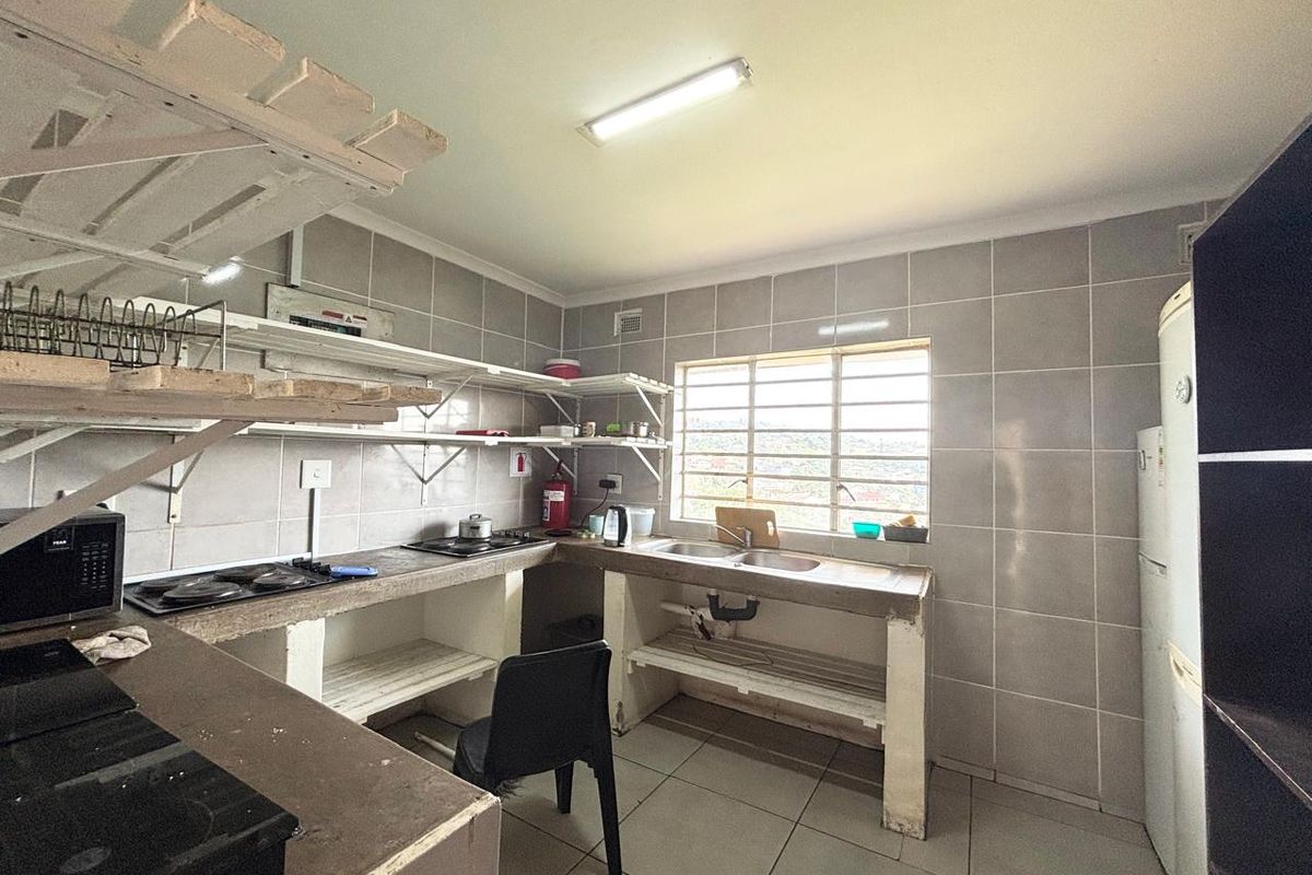Functional kitchen featuring tiled walls, concrete countertops with built-in hobs, double basin sink, and open shelving storage.
