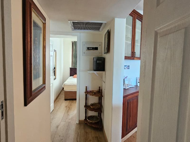 A view through a doorway into a hallway featuring wood-look flooring, built-in cabinetry, and access to an adjacent bedroom.