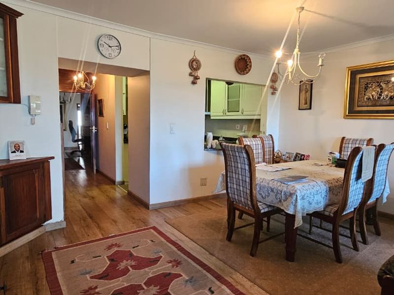 Open plan living and dining area featuring timber flooring, built-in cabinetry, and a serving hatch connecting to the kitchen.