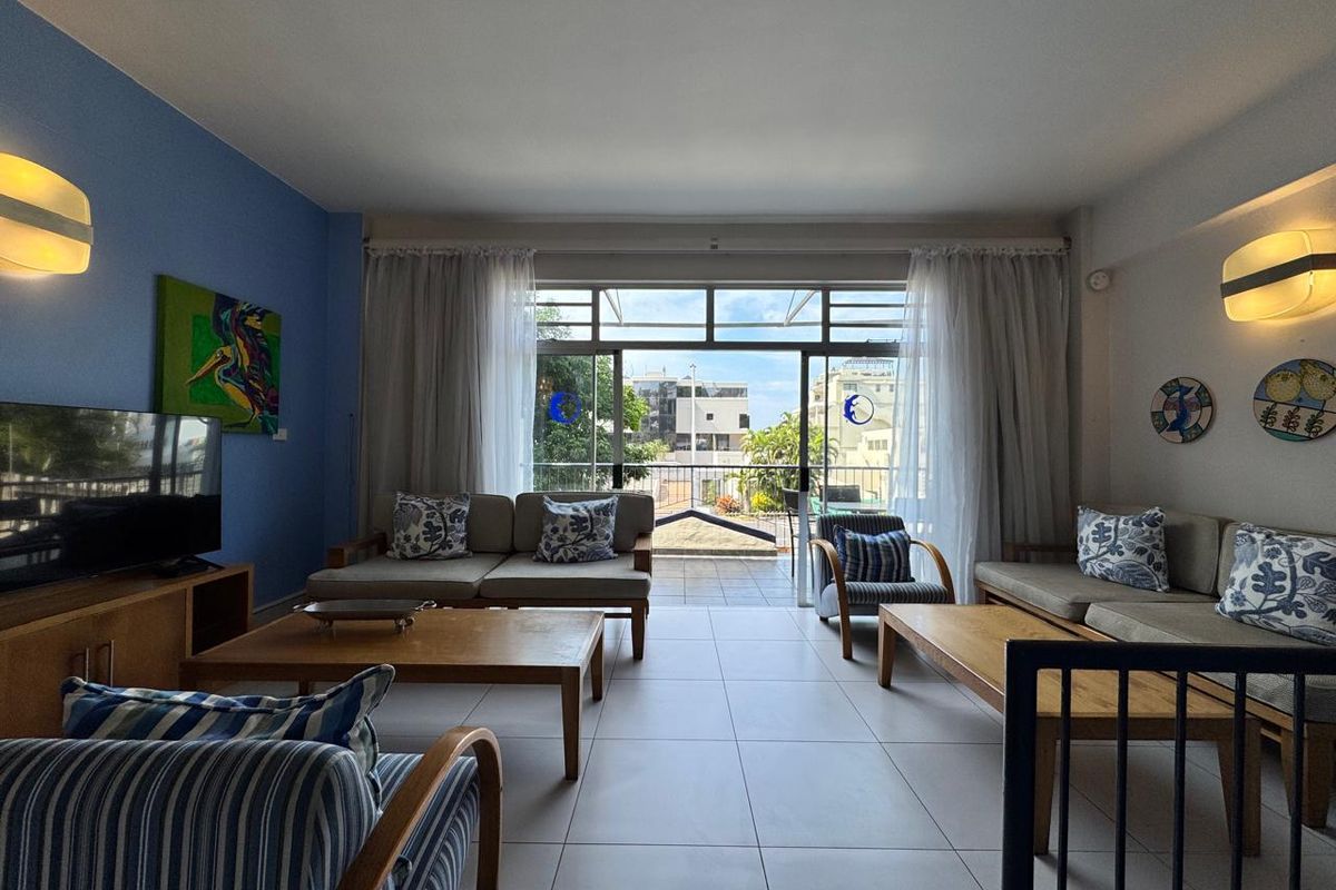 Spacious living room featuring large sliding glass doors that open onto a balcony, providing natural light and an urban view.