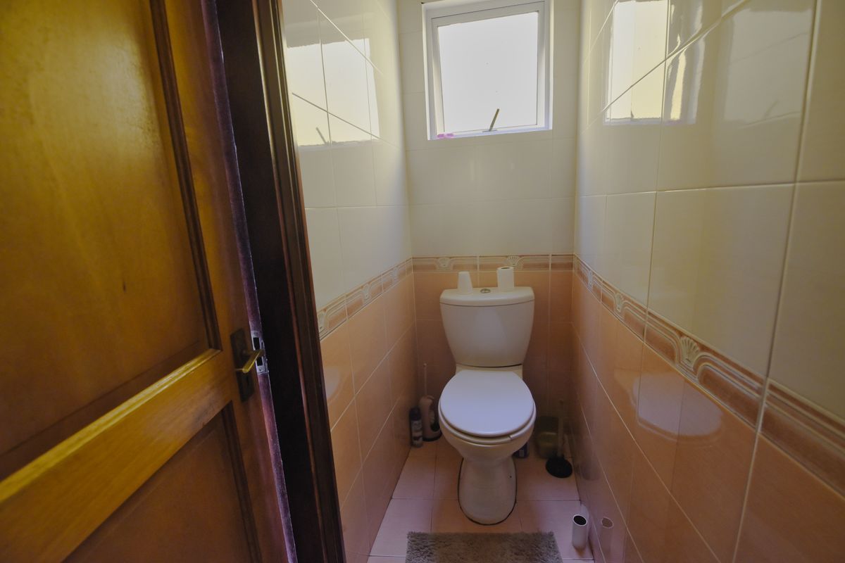 A compact guest toilet featuring ceramic wall tiles, a standard toilet suite, and a small ventilation window.