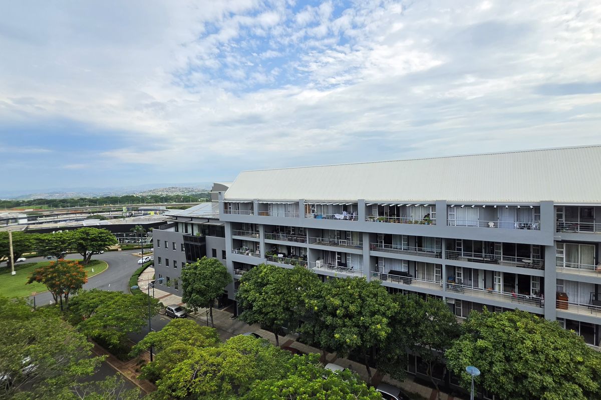 Elevated view of the apartment complex exterior, showcasing the building facade, balconies, and surrounding landscaped grounds.
