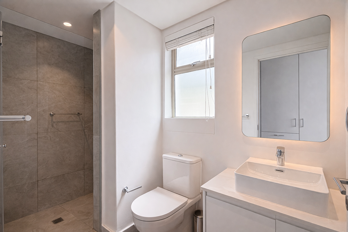Modern bathroom featuring a walk-in shower with large-format grey tiles, a contemporary vanity with a vessel sink, and a backlit mirror.