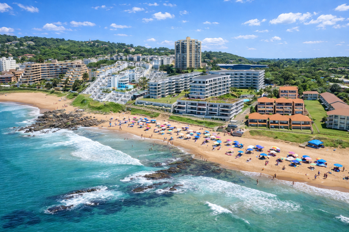 Aerial view of a coastal apartment complex situated directly along the beachfront, showcasing proximity to the ocean and surrounding residential landscape.