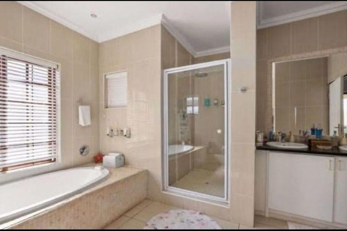 Spacious bathroom featuring a built-in bathtub, separate glass-enclosed shower, and a dual vanity with ample storage cabinetry.