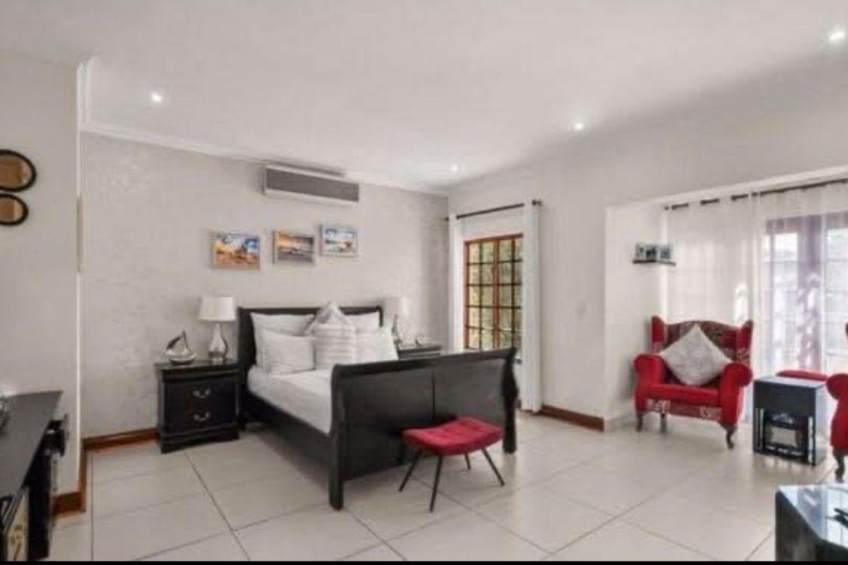 Spacious bedroom featuring tiled flooring, recessed downlighting, an integrated air conditioning unit, and direct access to the outdoors via french doors.