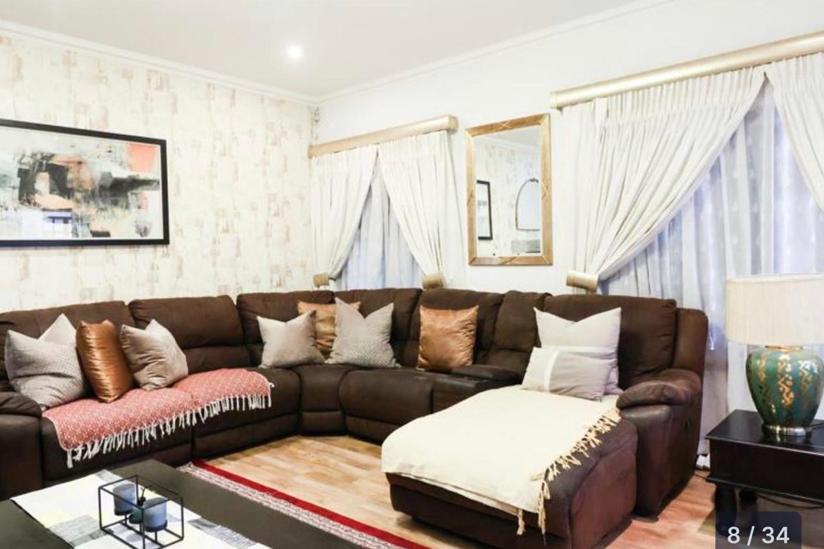 A comfortable living room featuring laminate flooring and recessed downlighting, providing a neutral base for interior design.